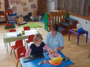 A child using toy computers with a teacher