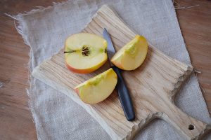 An apple cut in pieces on a board with a knife